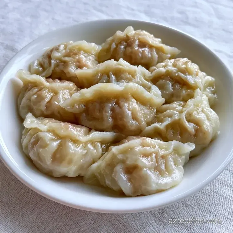 Dumplings de piel brillante y sedosa dispuestos en plato blanco con salsa oscura y semillas de s&eacute;samo espolvoreadas.